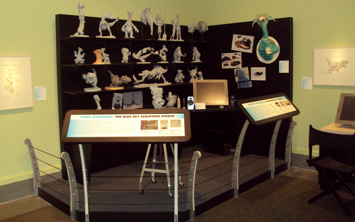 Custom display stage with reading rails. Display featuring a 3D artist's studio replica for the Ice Age and Rio movies including sculptures on shelving by Blue Sky Studios