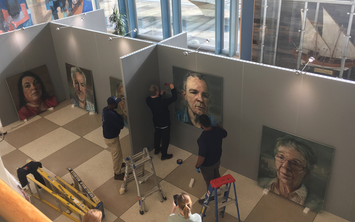 Workers hanging art on Gallery Rental Walls in gray for portrait art exhibit in the United Nations building in NYC