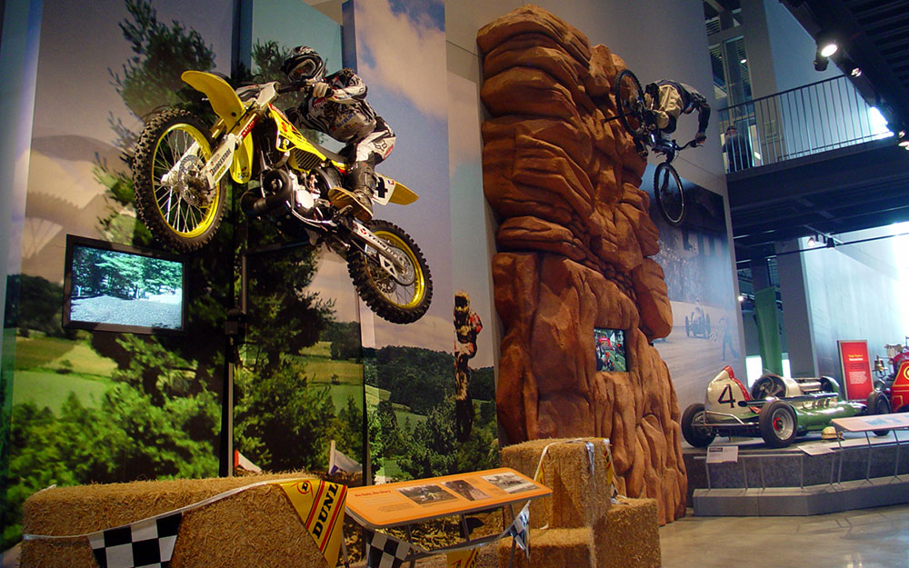 Custom rock wall with mounted bike and mannequin, wall graphics and monitor for America on Wheels museum exhibit