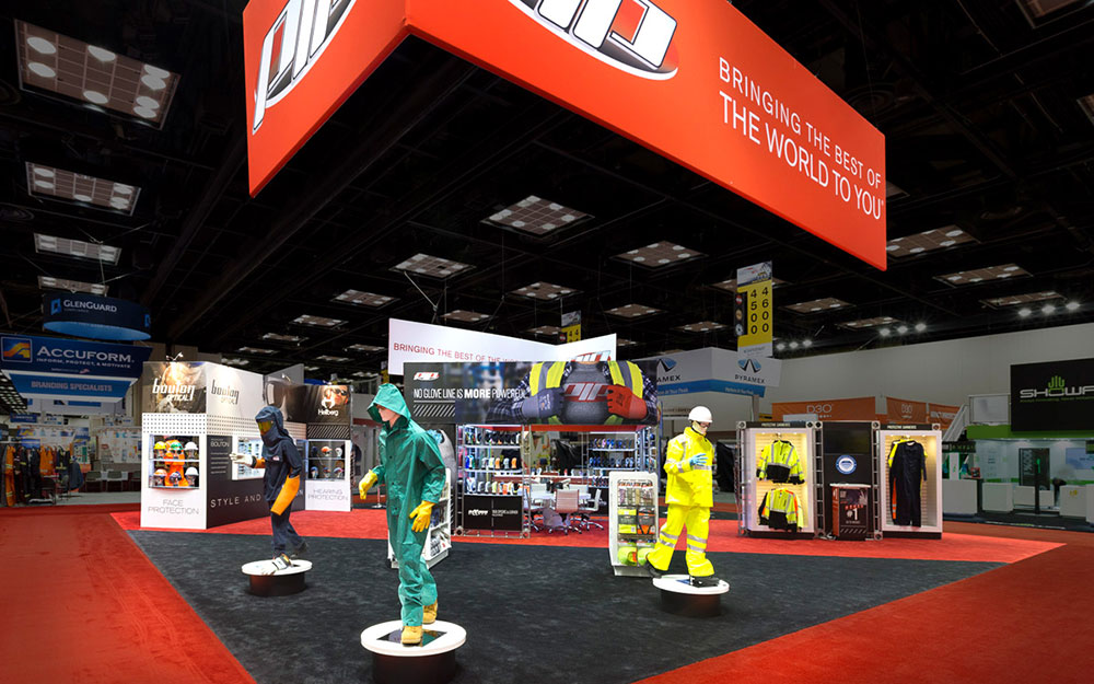 Trade show booth exhibit for PIP with mannequins on pedestals, custom built storage table, fabric wrapped header and graphic wall storage rooms